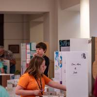 attendees laughing in hallway in front of posters from student project showcase